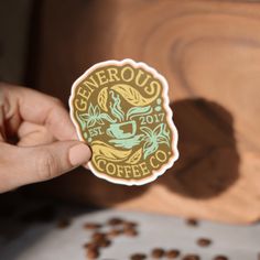 a person holding up a sticker with coffee beans in front of them and the words generous coffee on it