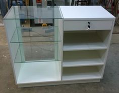 a white cabinet with glass shelves on the front and bottom, sitting in a warehouse