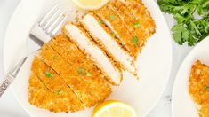 two white plates topped with chicken cutlets and garnished with parsley