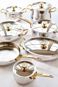 a group of pots and pans sitting on top of a white tablecloth with gold handles