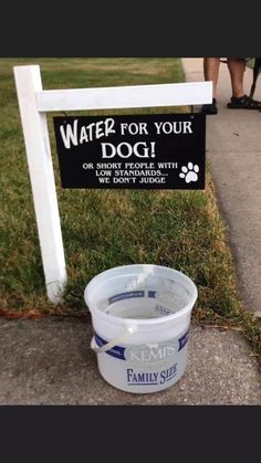 a bucket of water sitting in front of a sign that says water for your dog