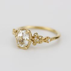 a gold ring with an oval cut diamond in the center and small white stones on each side