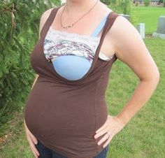 a pregnant woman standing in the grass with her hands on her hips and looking at the camera