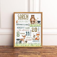 an animal themed birth poster is displayed on a wooden table in front of a white wall