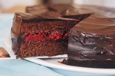 a piece of chocolate cake on a plate with the rest of the cake in front of it