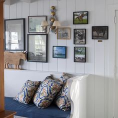 a blue couch with pillows on it in front of pictures and other things hanging on the wall