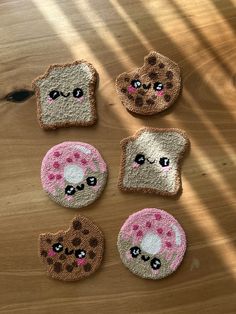 four pieces of toast with pink and brown designs on them sitting on a wooden table