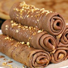 three rolled up chocolate desserts sitting on a white plate with sprinkles