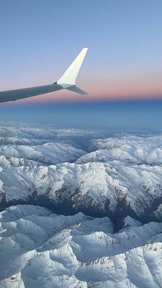 an airplane wing flying over snow covered mountains