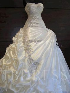 a white wedding dress on display in front of a black background