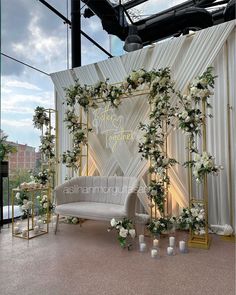 an outdoor wedding ceremony setup with white flowers and greenery on the back drop wall