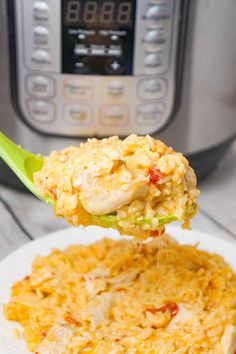 a spoon full of rice on top of a white plate with an instant pressure cooker in the background