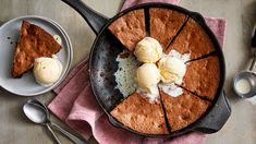 a skillet with some ice cream on top of it next to two plates and spoons