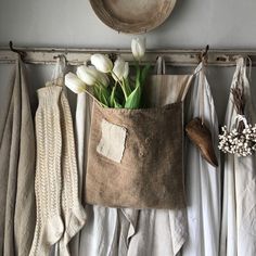 tulips and other flowers are in a bag hanging on a clothes rack with sweaters