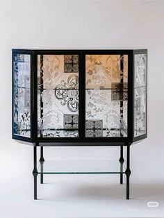 a black and white cabinet with glass doors on it's sides, in front of a wall