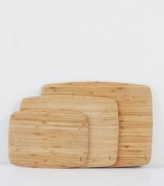 three bamboo cutting boards sitting next to each other on a white counter top against a wall