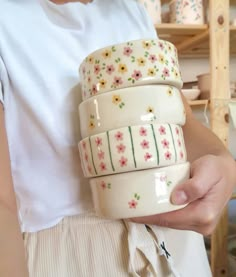 a woman is holding three cups in her hands and she has one on her arm