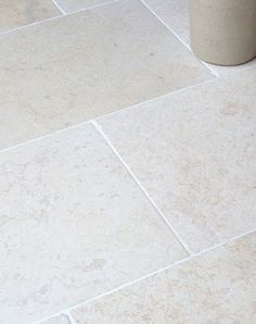 a white toilet sitting on top of a tiled floor next to a trash can in a bathroom