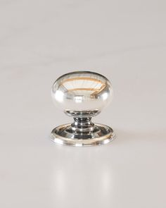 a chrome plated knob on a white surface with no one in the photo looking at it