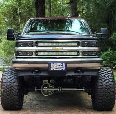 the front end of a pickup truck parked in a wooded area