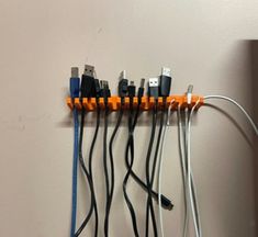 a bunch of wires are connected to each other on a wall mounted rack with orange and black cords