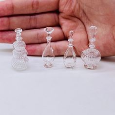 three small glass items in the palm of a person's hand on a white surface