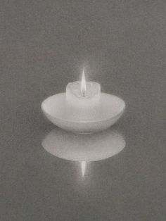 a lit candle sitting on top of a white plate