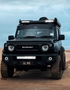 the front end of a black four - doored suv parked on a sandy beach