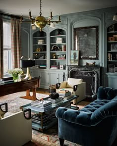 a living room filled with furniture and bookshelves next to a window covered in curtains