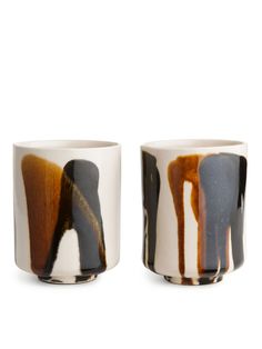 two cups with different designs on them sitting next to each other in front of a white background