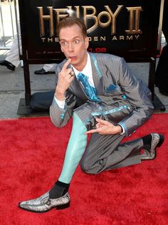 a man sitting on top of a red carpet next to a sign