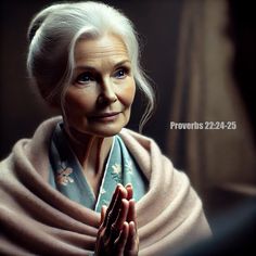 an older woman with white hair wearing a blue shawl and holding her hands together