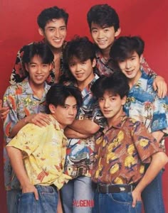 the group of young men are posing together for a photo in front of a red background