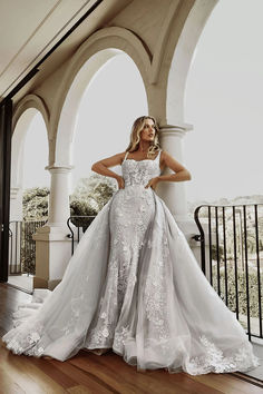 a woman in a wedding dress standing on a balcony