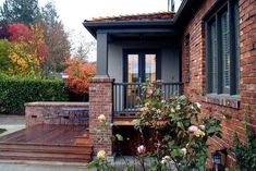 a brick house with steps leading up to the front door and flowers growing on the porch