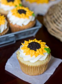 cupcakes decorated with sunflowers and white frosting on top of a table