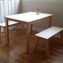 a wooden table with two benches next to it on a hard wood floor in front of a radiator