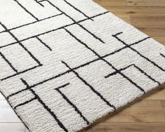 a white and black rug on top of a wooden floor