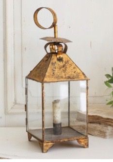 an old fashioned lantern is sitting on a table next to some flowers and other items