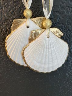 two seashells are hanging on the wall with gold foiled decorations around them