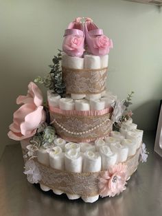 a three tiered diaper cake is adorned with pink roses and baby swaddles