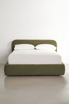 a bed with two pillows on top of it in a white room next to a wall