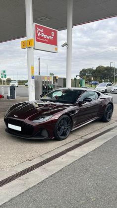 a maroon sports car parked in front of a gas station with no one around it