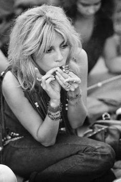 a black and white photo of a woman sitting on the ground with her hands in her mouth