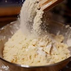 a wooden spoon pouring flour into a metal bowl