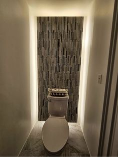 a bathroom with a toilet and tiled walls