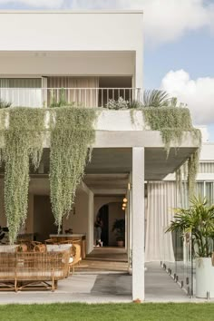 an outdoor patio with wicker furniture and plants on the balconies above it