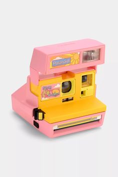 a pink and yellow polaroid camera sitting on top of a table