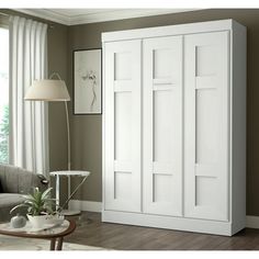 a living room filled with furniture and a white cabinet in front of a large window