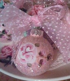 a pink ornament sitting on top of a plate covered in bows and flowers